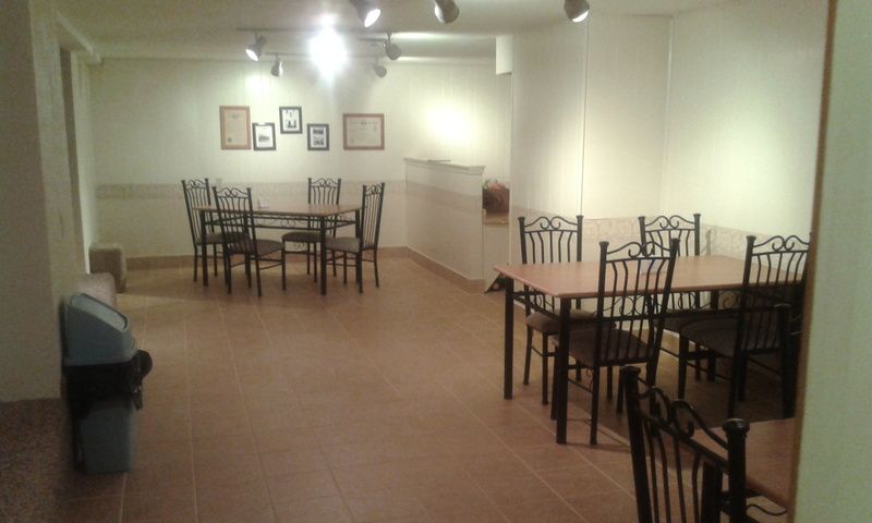 A dining room with tables and chairs and a trash can.