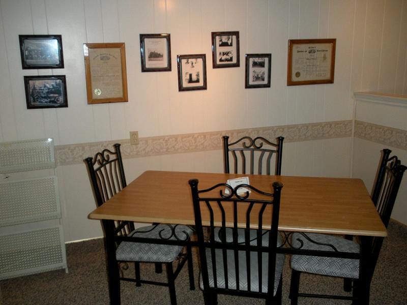 A dining room with a table and chairs and pictures on the wall