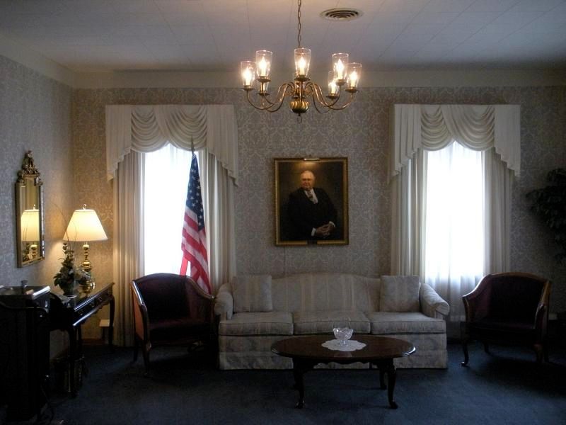 A living room with a couch and chairs and a painting on the wall