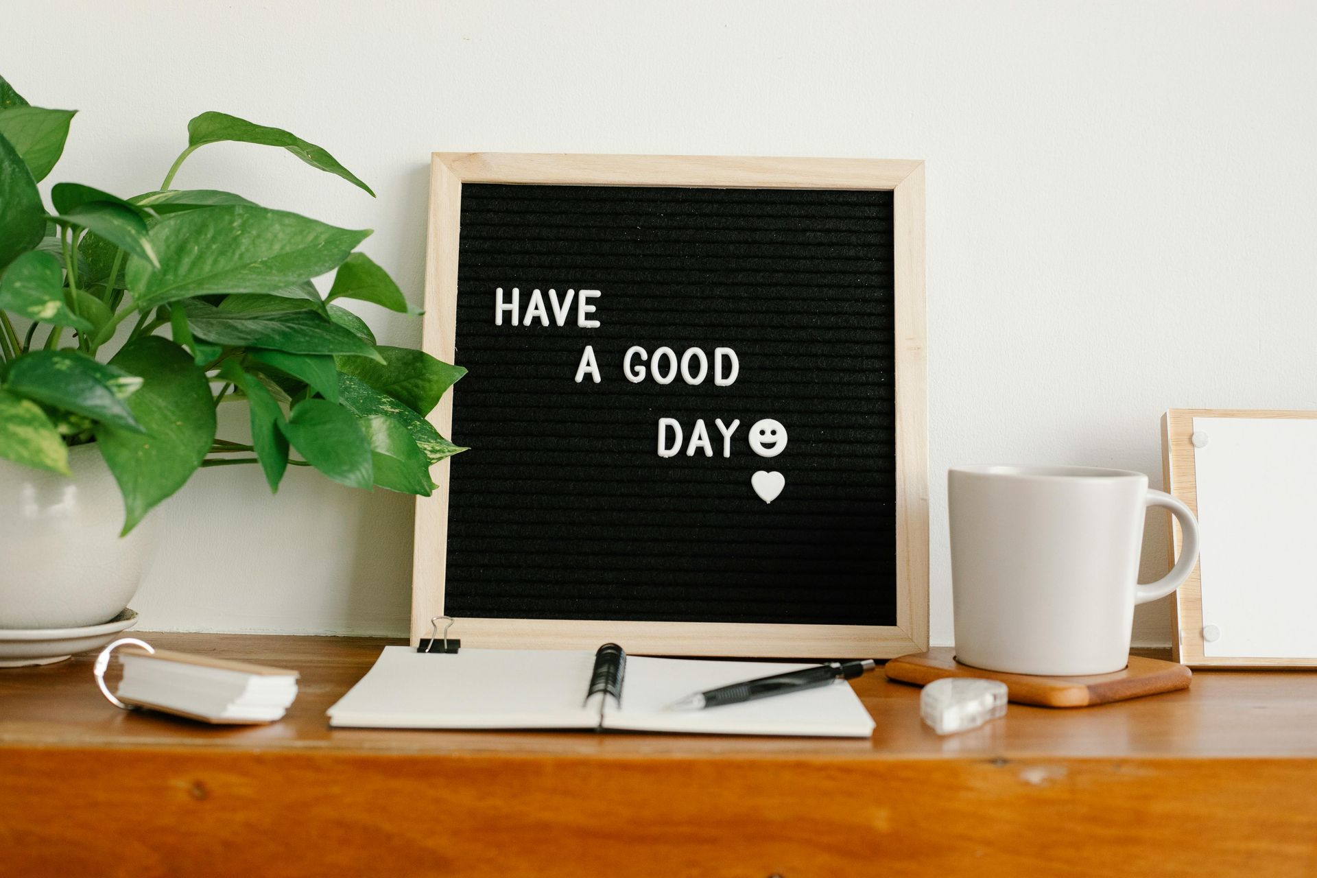 Een bureau met een plant, een koffiemok en een letterbord met de tekst 