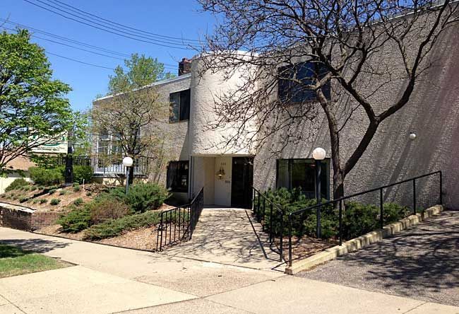 a large white building with stairs leading up to it and a tree in front of it .