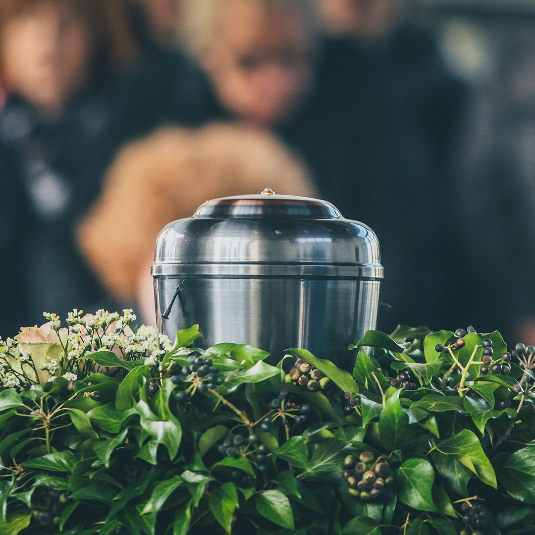 a metal urn is sitting on top of a lush green bush .