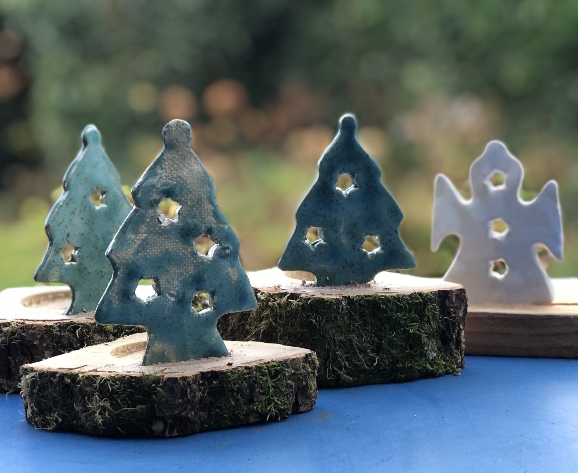 Keramische kerstboom en engeltjes als theelichthouders op houten schijven, geschikt voor buiten.