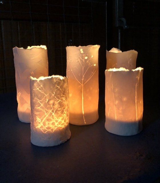 Vijf lichtgevende papieren lantaarns met een gestructureerd ontwerp, die van binnenuit verlicht worden.