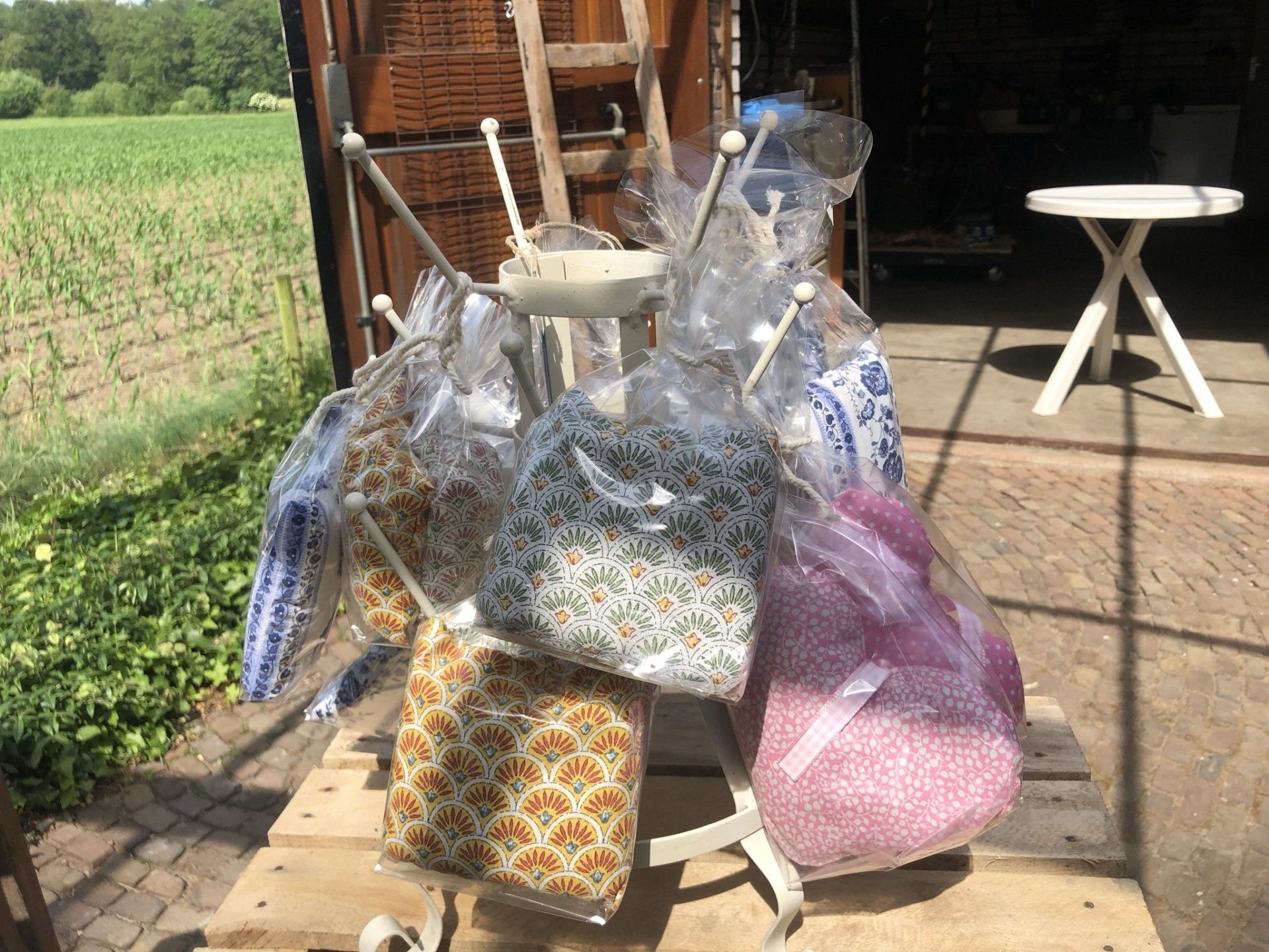 Kleurrijke tassen hangen buiten te drogen op een droogrek, met een veld op de achtergrond.