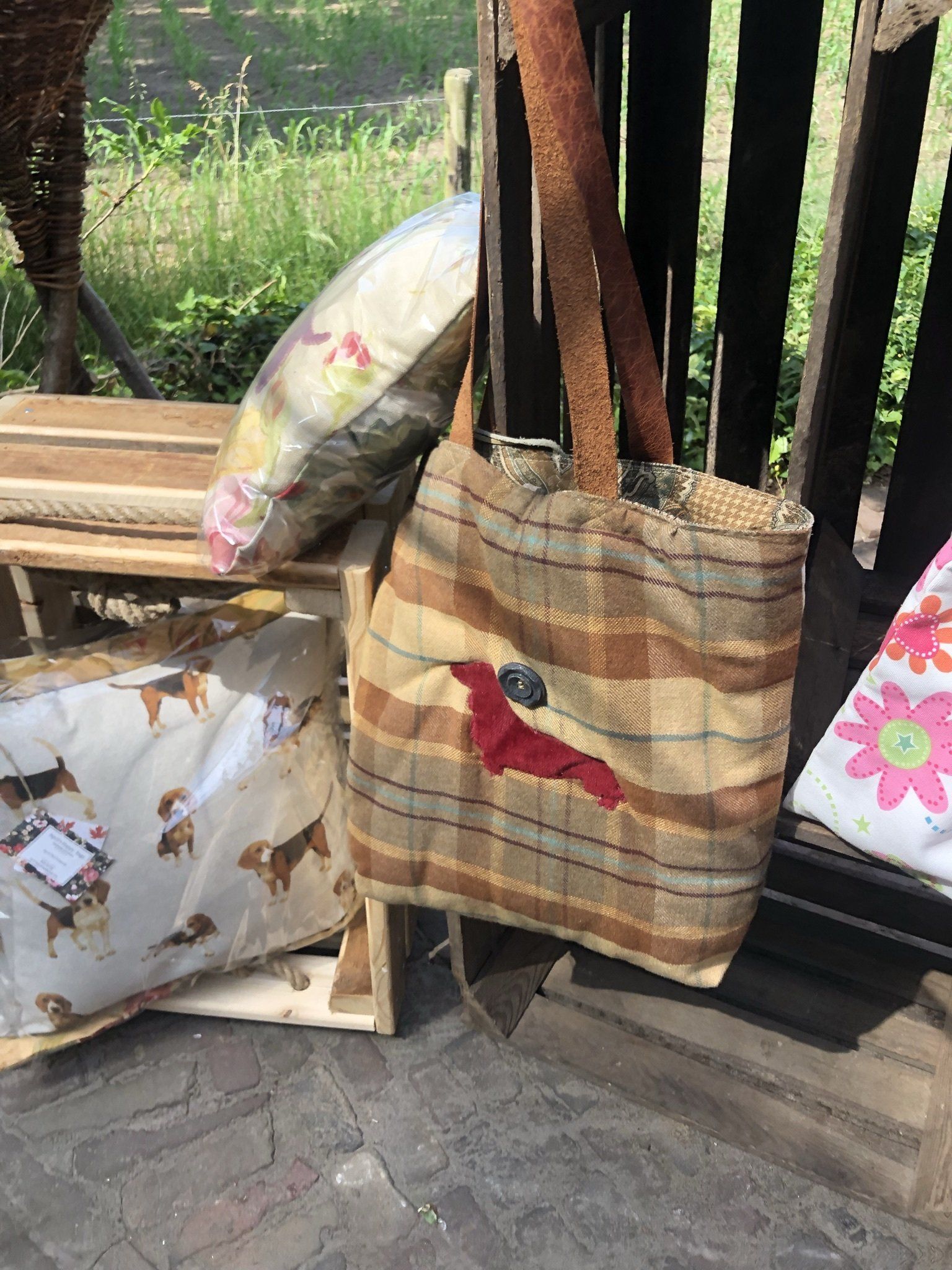 Draagtas met rode applicatie op een houten pallet, naast kussens en een sierkussen.