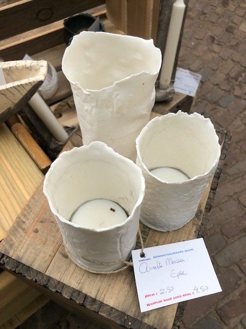 Drie witte, gestructureerde keramische kaarsenstandaards op een houten ondergrond.