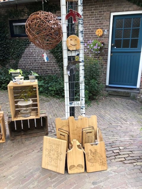 Een tentoonstelling van houten snijplanken en decoratieve voorwerpen op een binnenplaats.
