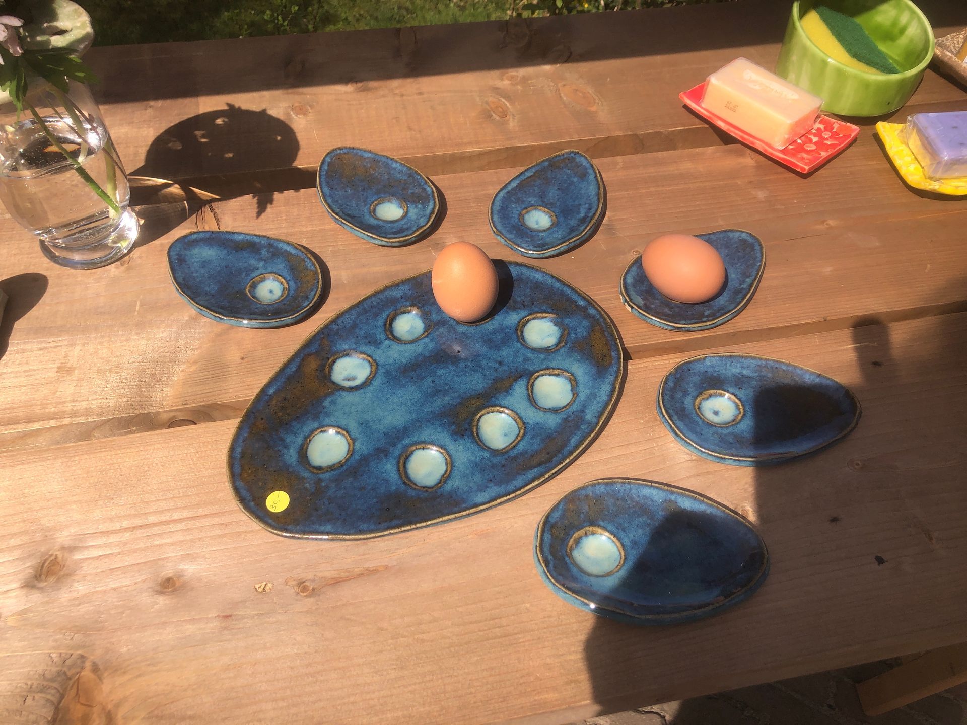 Blauwe keramische eierschalen met eieren, op een houten tafel buiten.