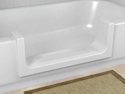 A white bathtub with a door and a rug on the floor.