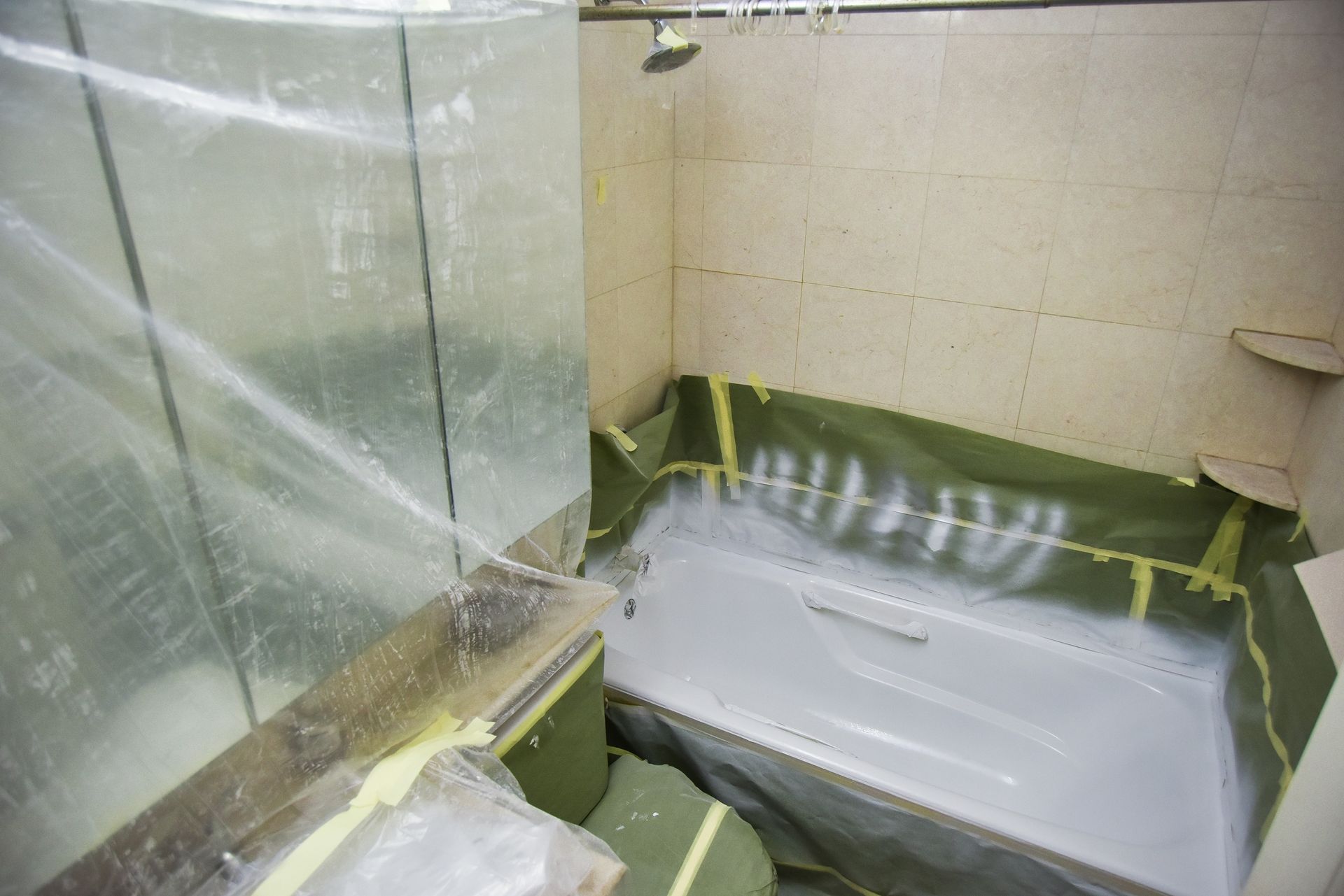 A bathroom with a bathtub covered in plastic and a shower.