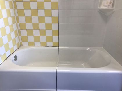 A bathtub in a bathroom with yellow and white checkered tiles.