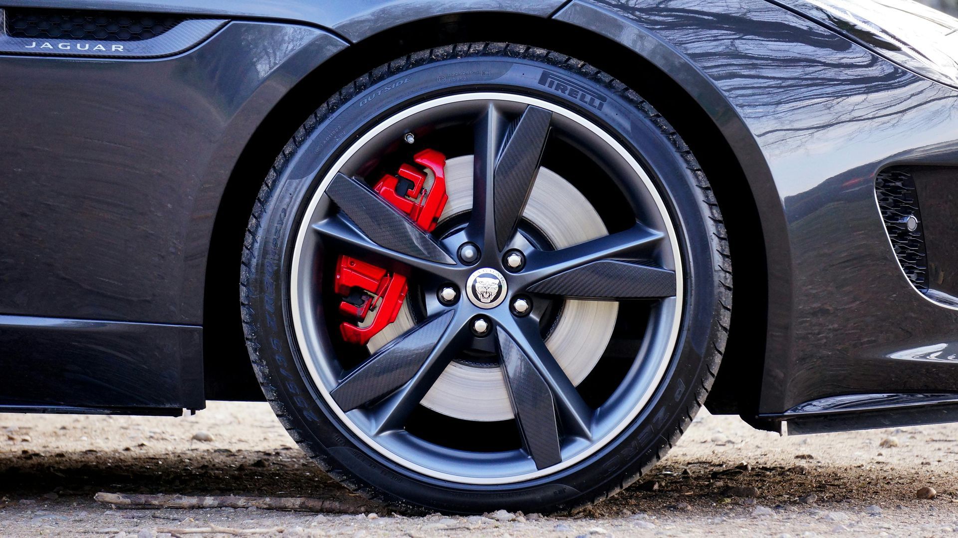 Close-up of a black sports car wheel with red brake caliper and silver rim.