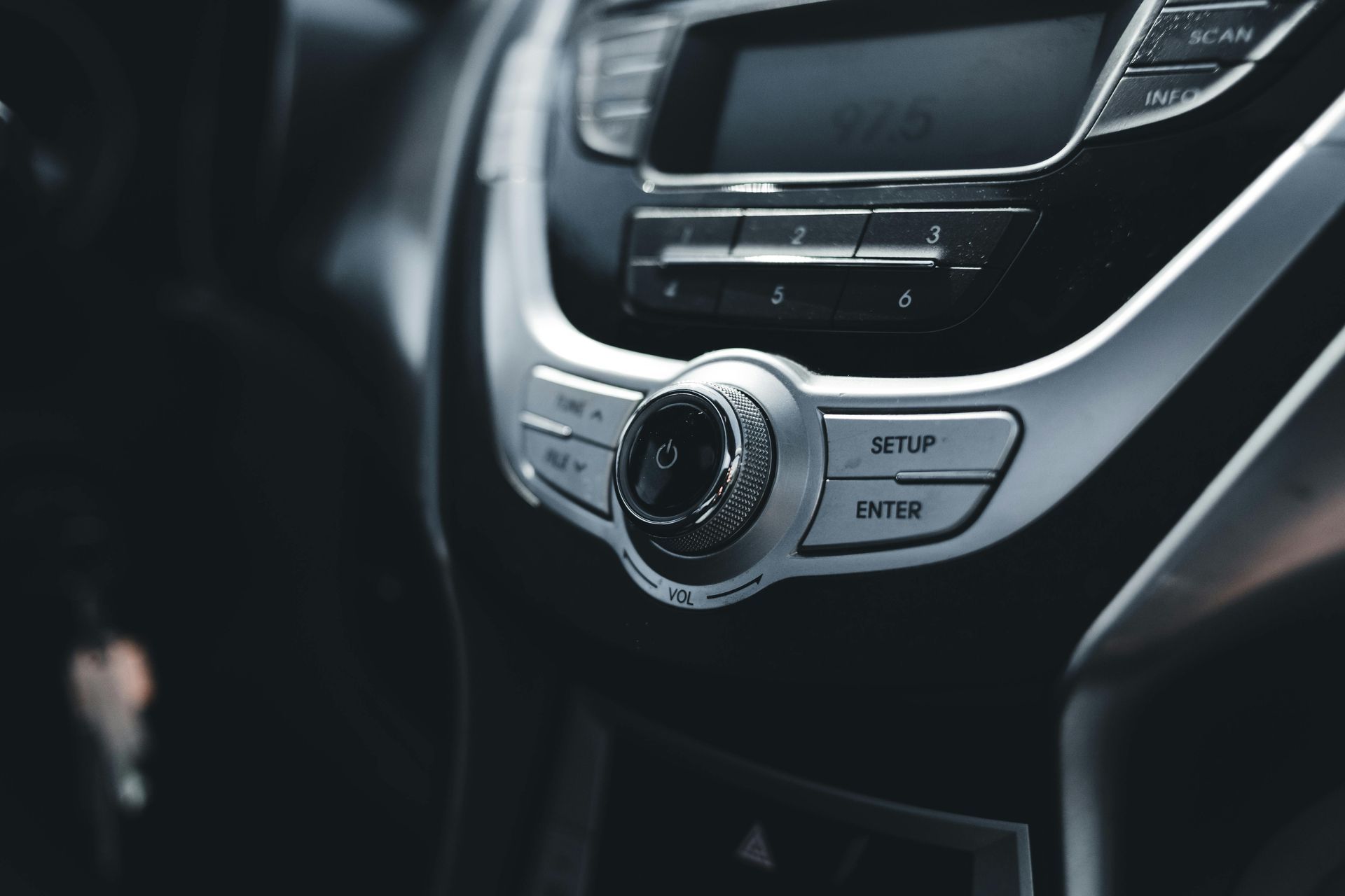 Close-up of a car dashboard center console with climate controls and buttons in silver trim