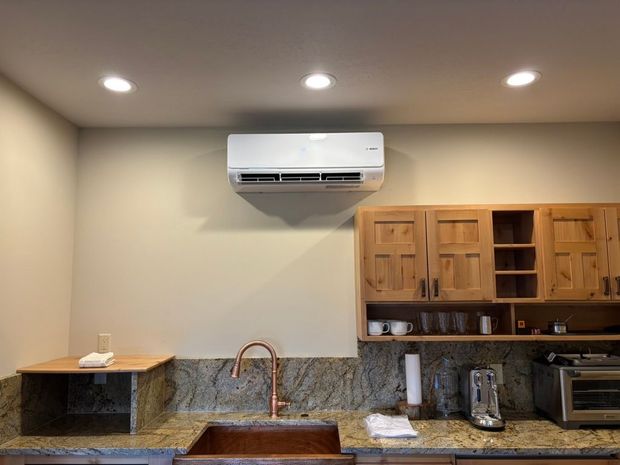 Modern kitchen with wood cabinets, granite counters, copper sink, and a wall-mounted air conditioner