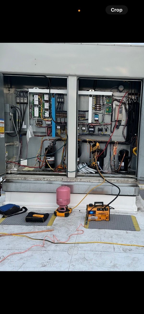 Two open electrical cabinets with tools on the floor in a utility room, wires and panels exposed