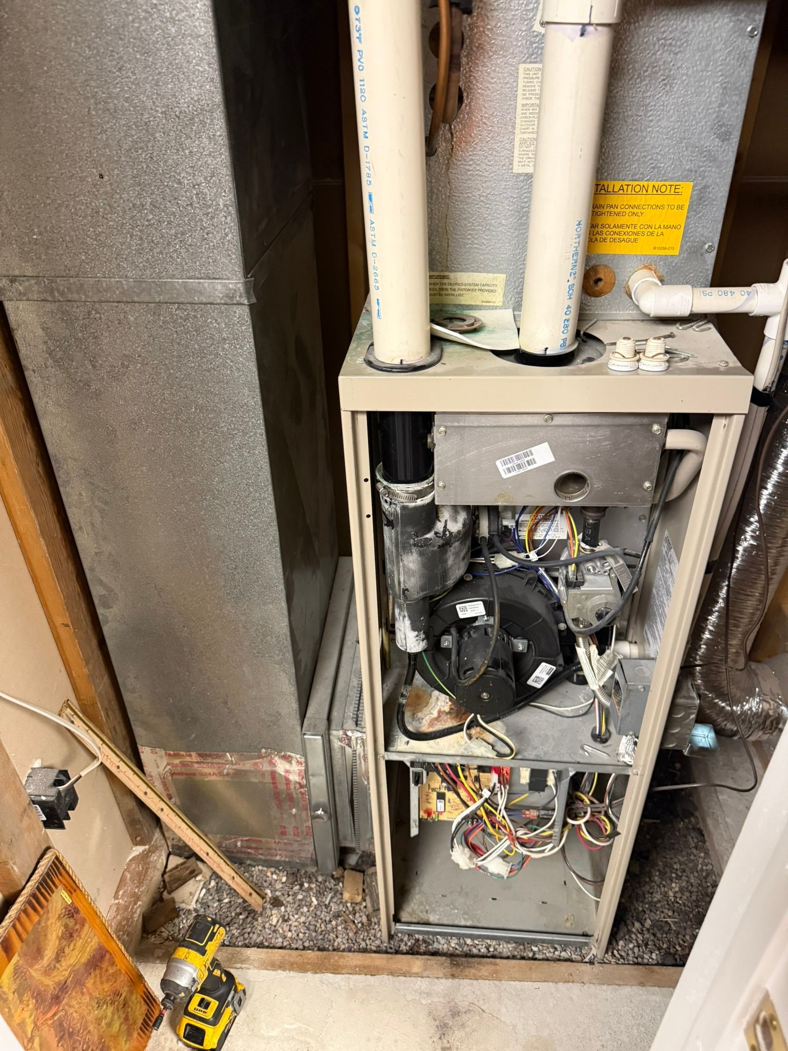 Open utility panel with exposed wiring and pipes in a basement or crawlspace.