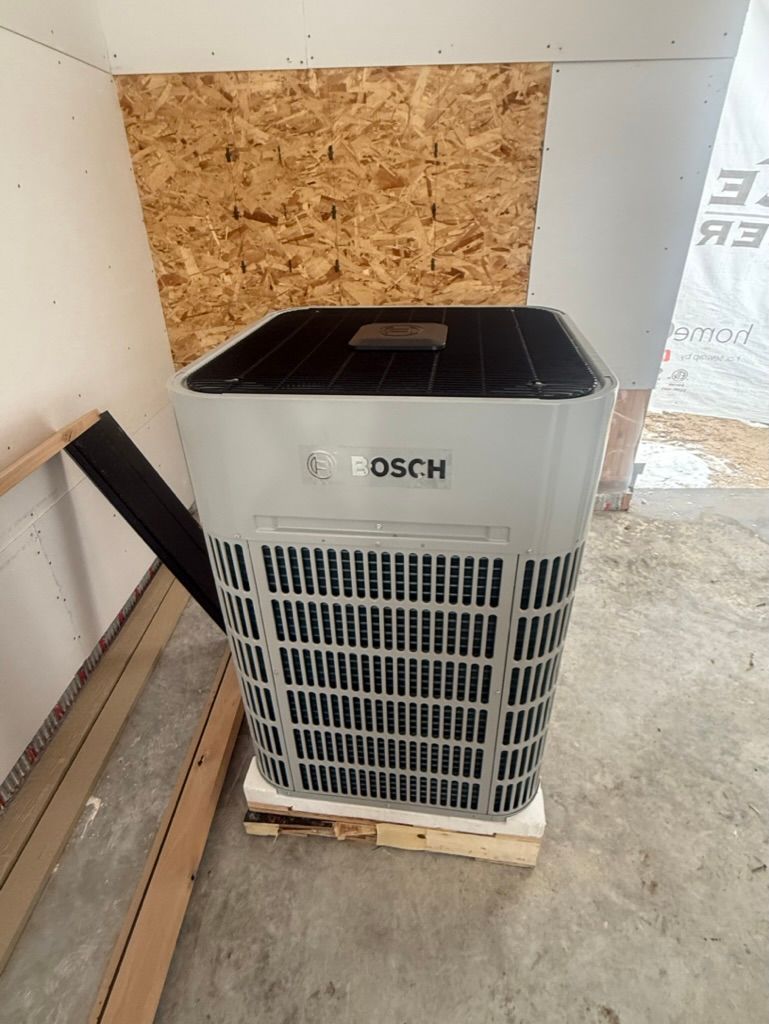 Bosch air conditioner unit standing on a concrete floor beside plywood boards.