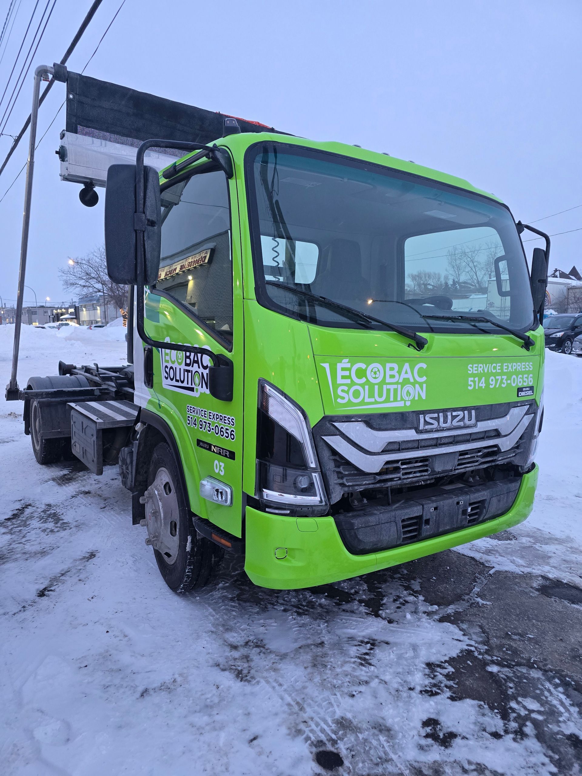 Un camion vert est garé dans la neige.
