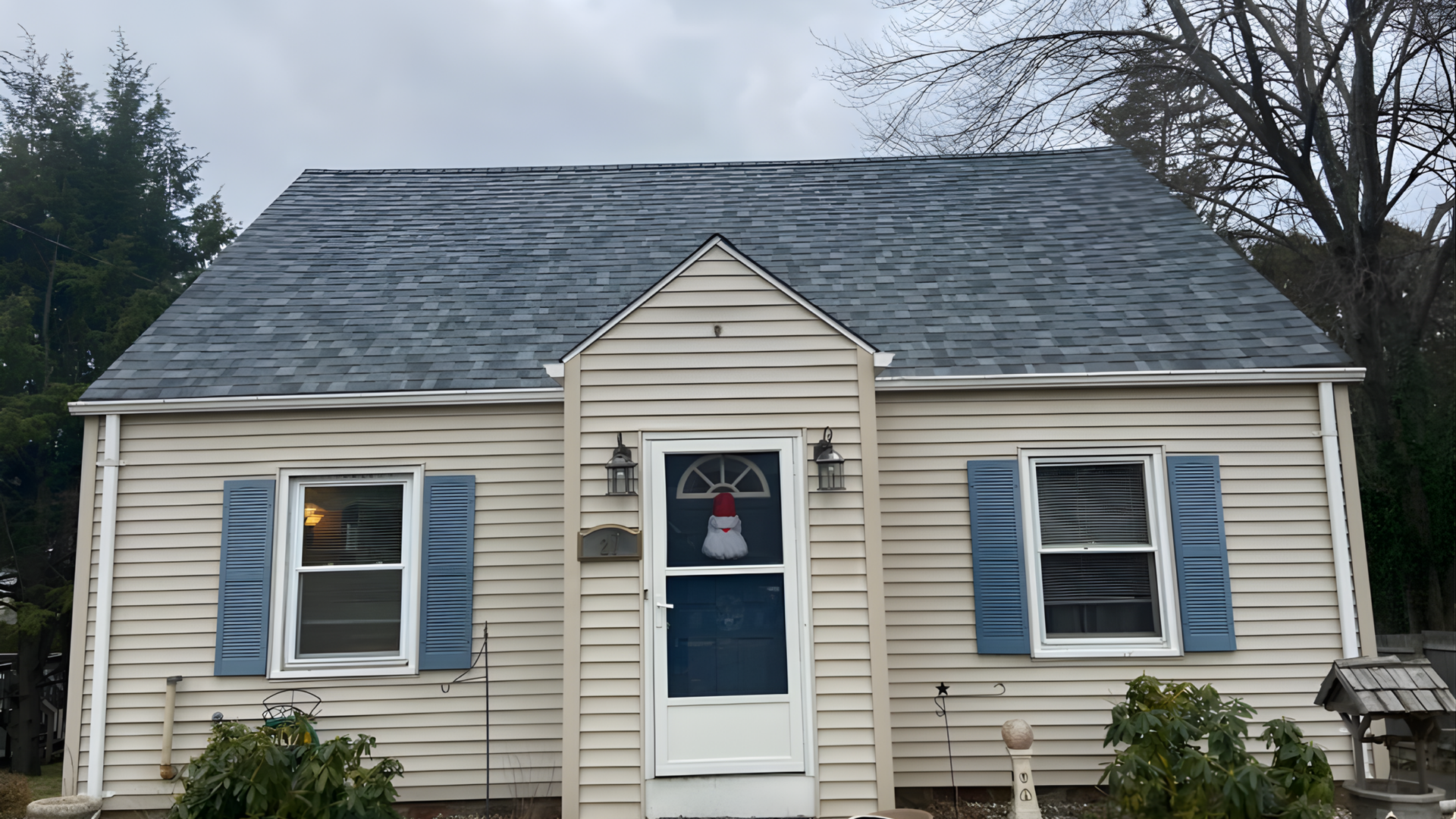 Gray shingle roof with a small vent, overlooking a yard and house in the background