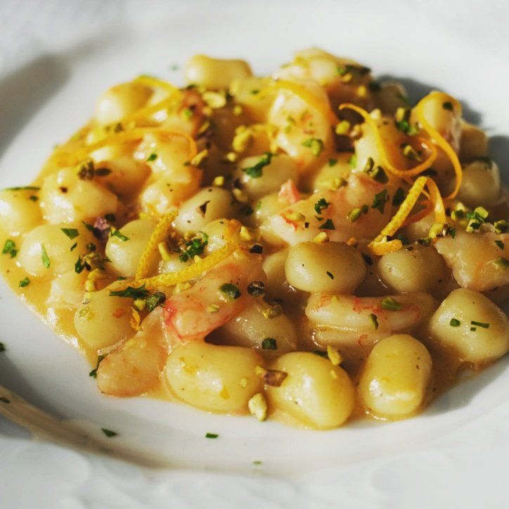 Un piatto bianco condito con gnocchi e gamberi