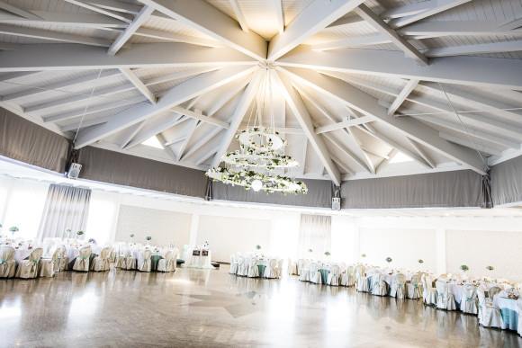 Una grande stanza vuota con tavoli e sedie e un lampadario appeso al soffitto.