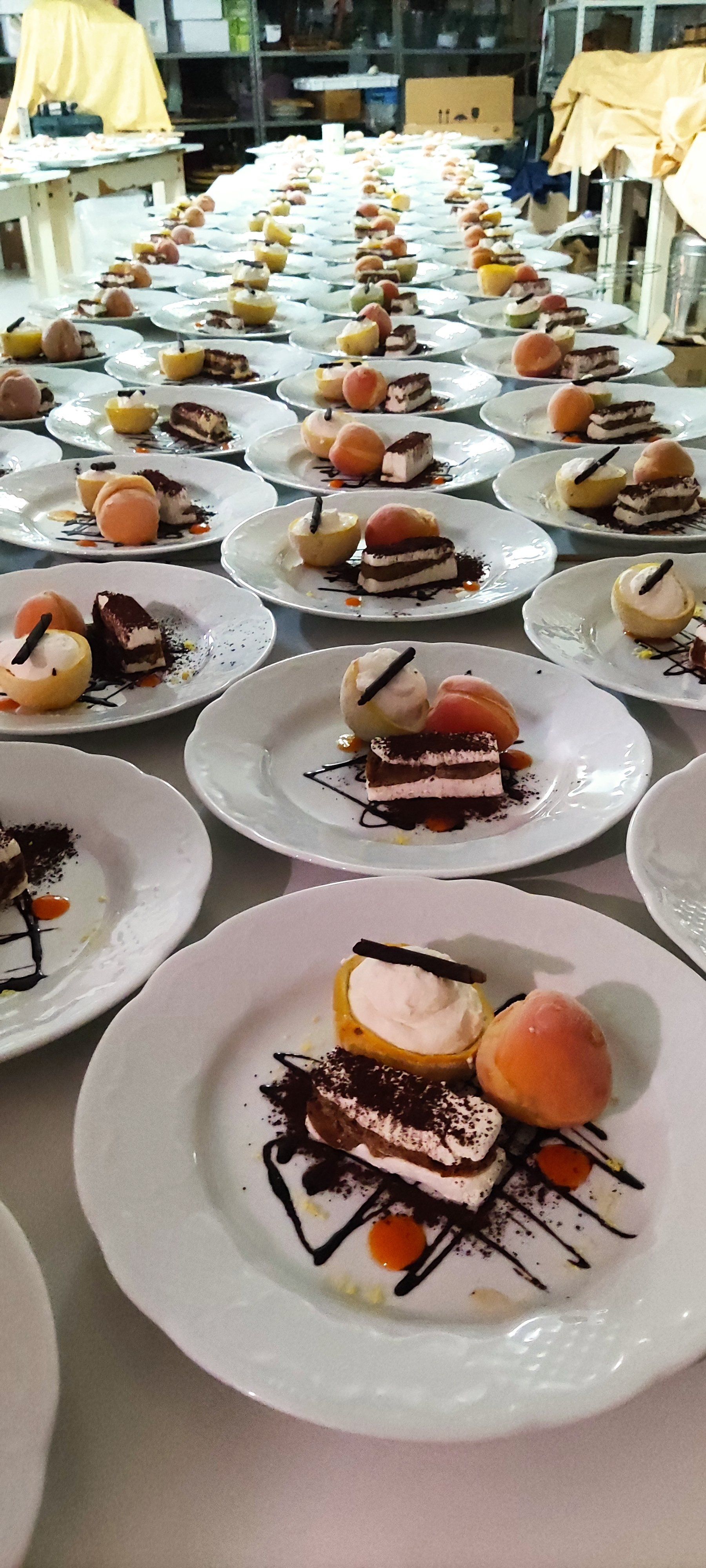 File di dessert impiattati su un tavolo da banchetto, con torte ricoperte di cioccolato e guarnizioni di frutta.