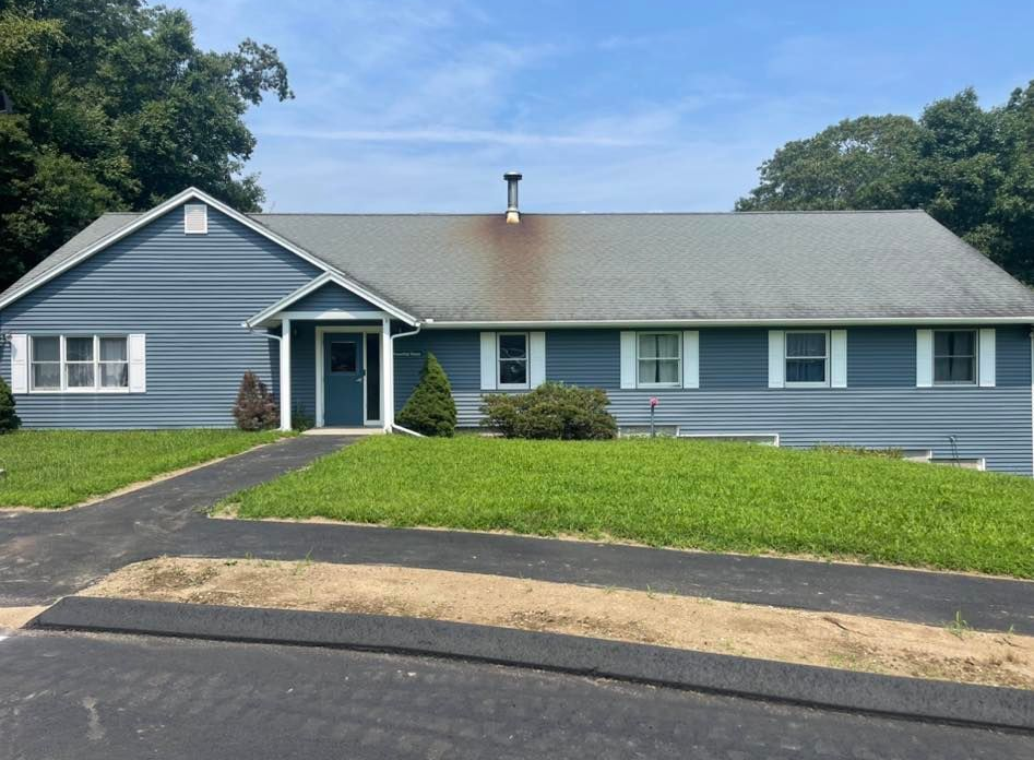 Blue house with a black driveway and green grass in front.