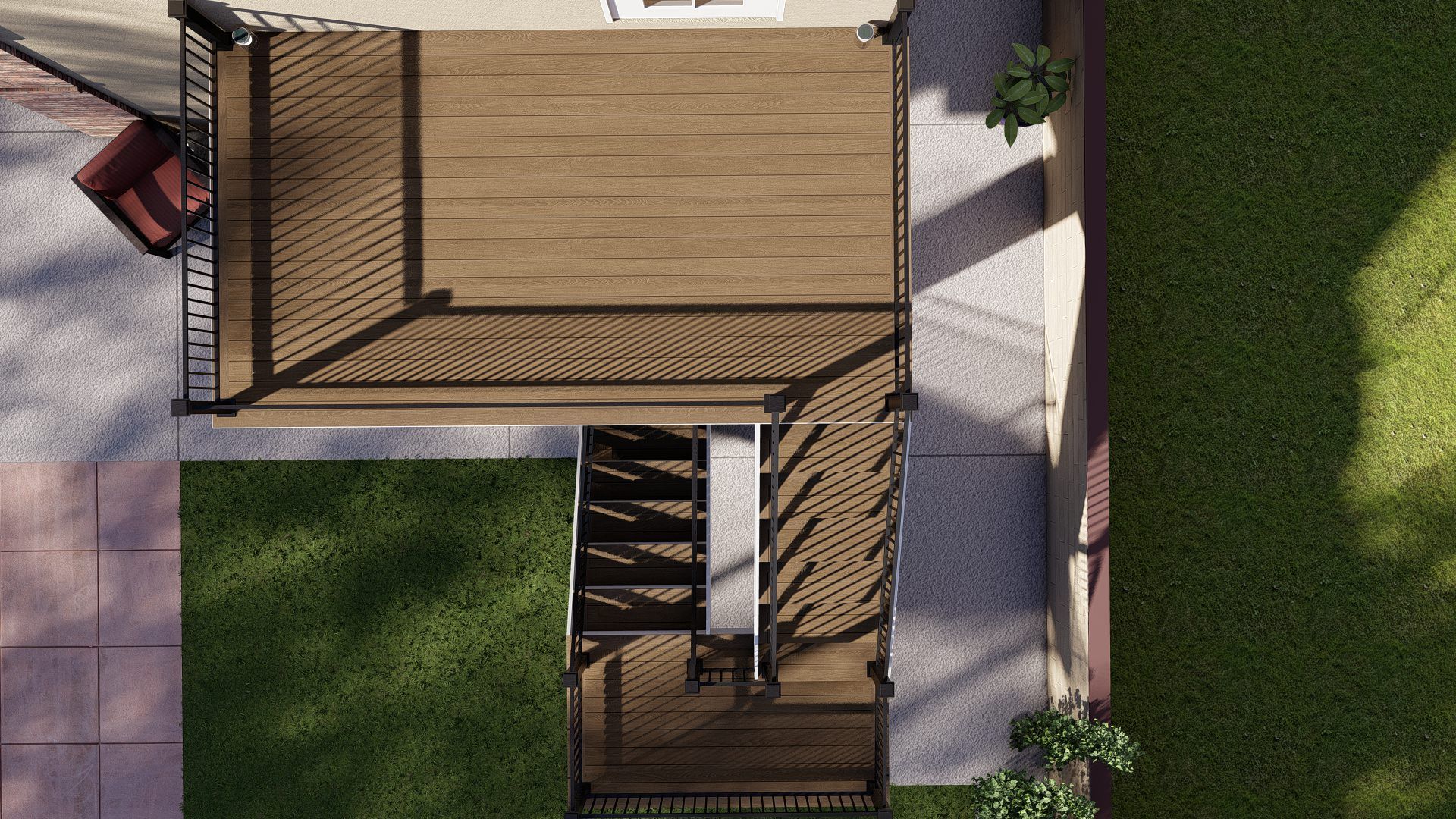 Top-down view of a backyard deck and stairway beside a grassy lawn and paved patio.