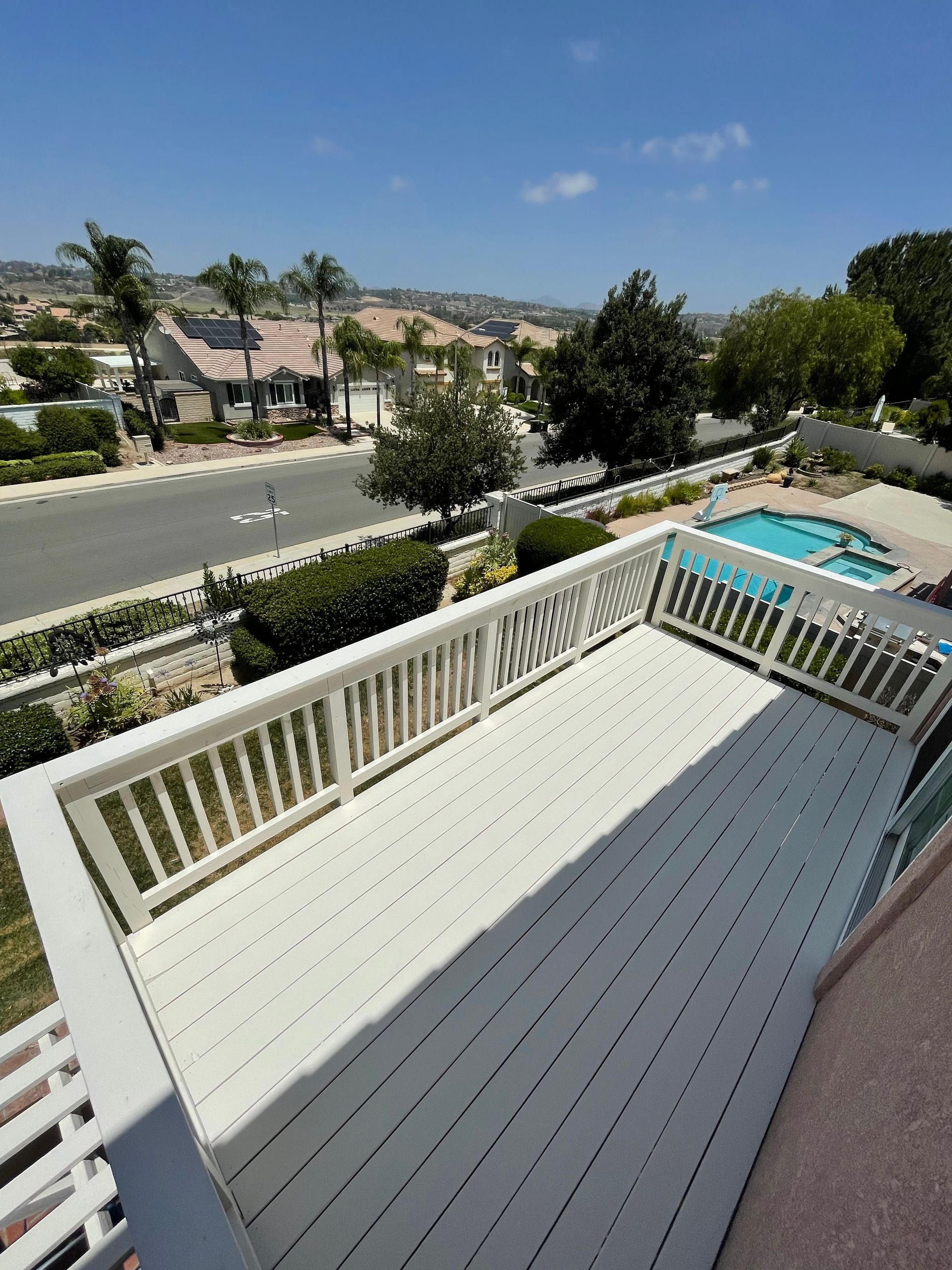 Balcony overlooking a street, rooftops, and a swimming pool on a sunny day