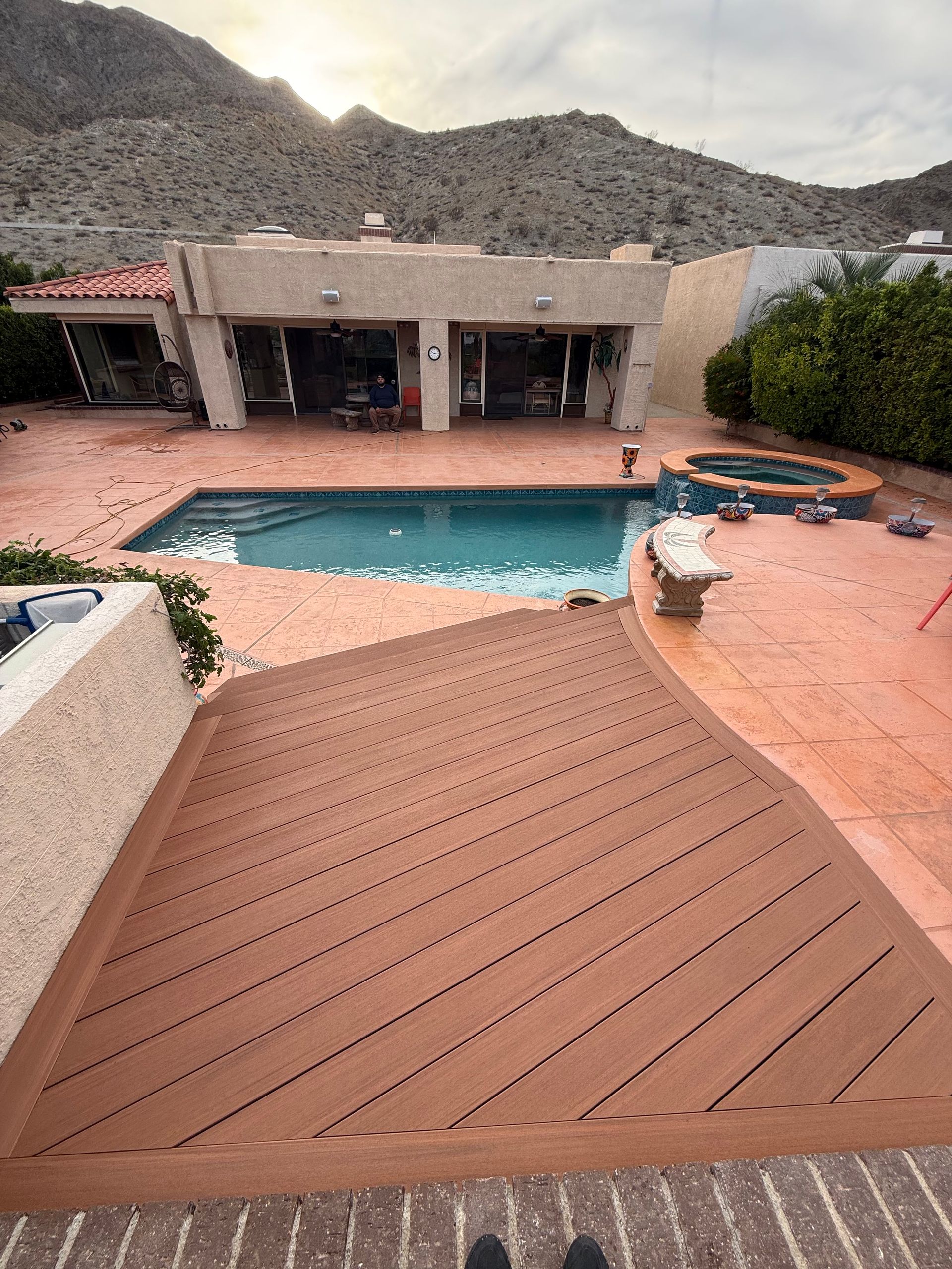 Backyard patio with a swimming pool, lounge chairs, and desert hills in the background