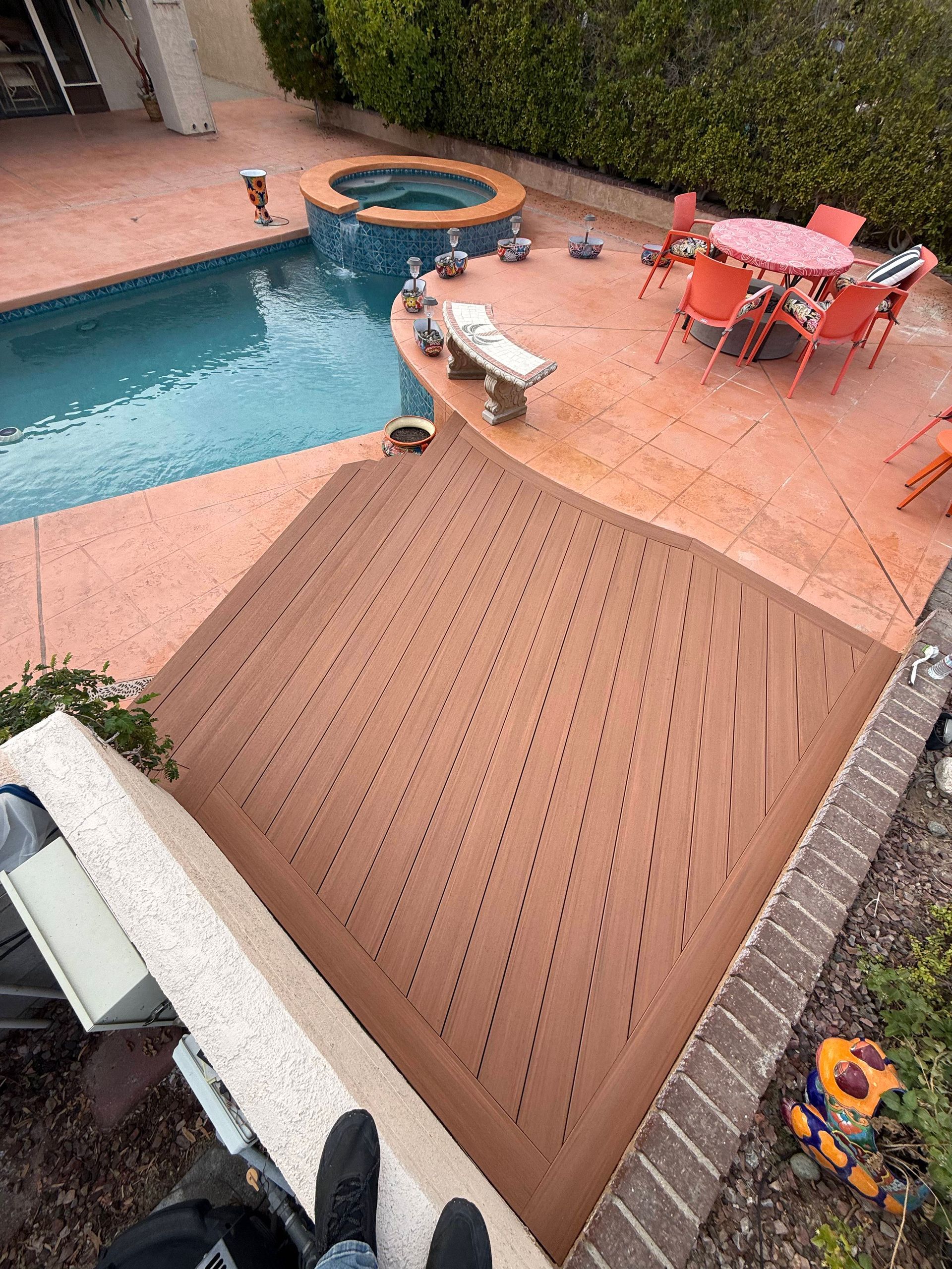 Backyard pool deck with hot tub, patio table and chairs, and a wooden deck extension
