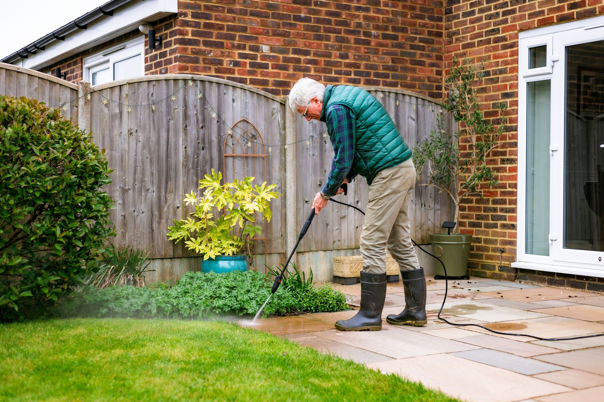 A man is cleaning a patio with a high pressure washer.
