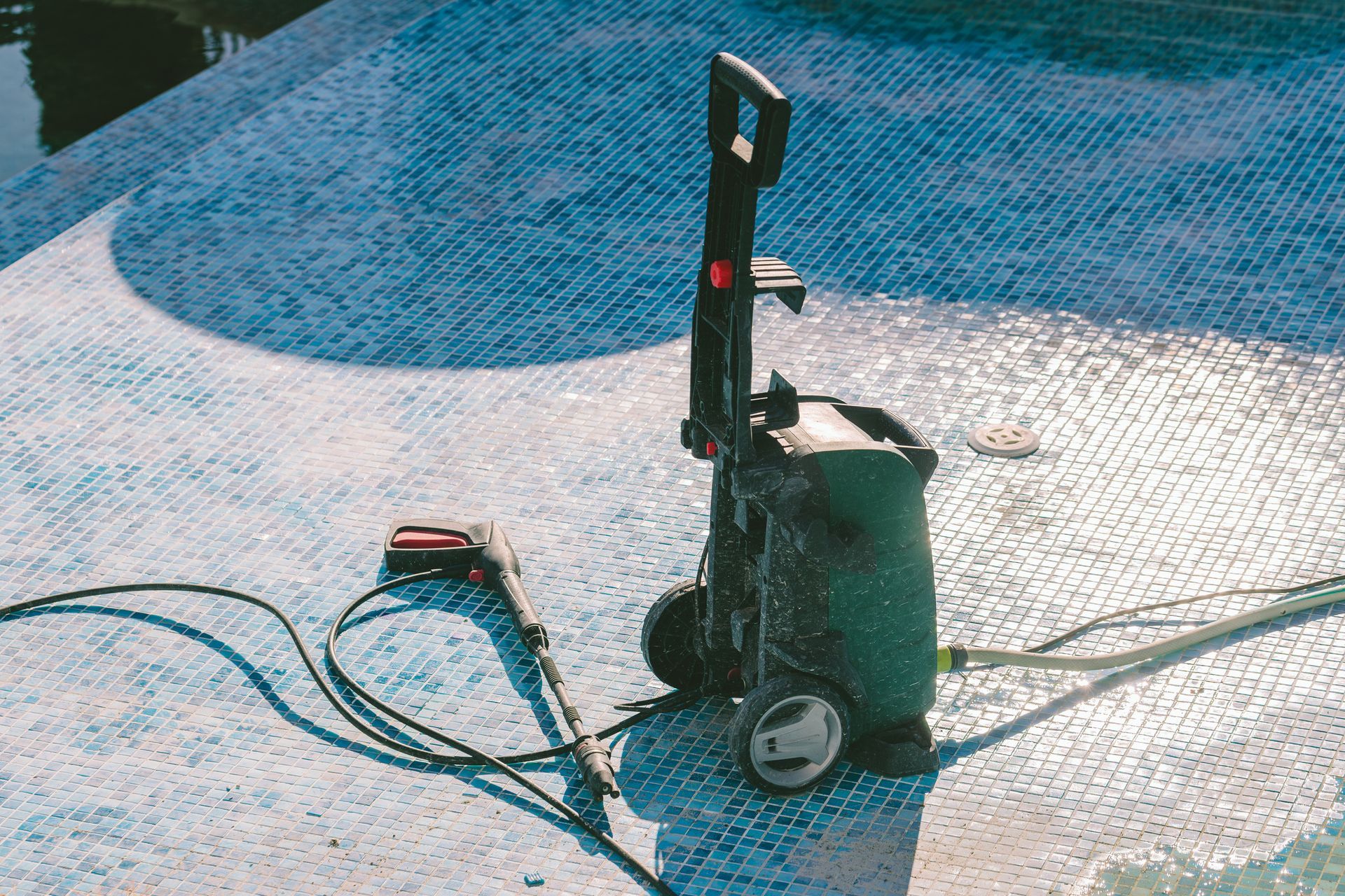 A high pressure washer is sitting on the ground next to a pool.