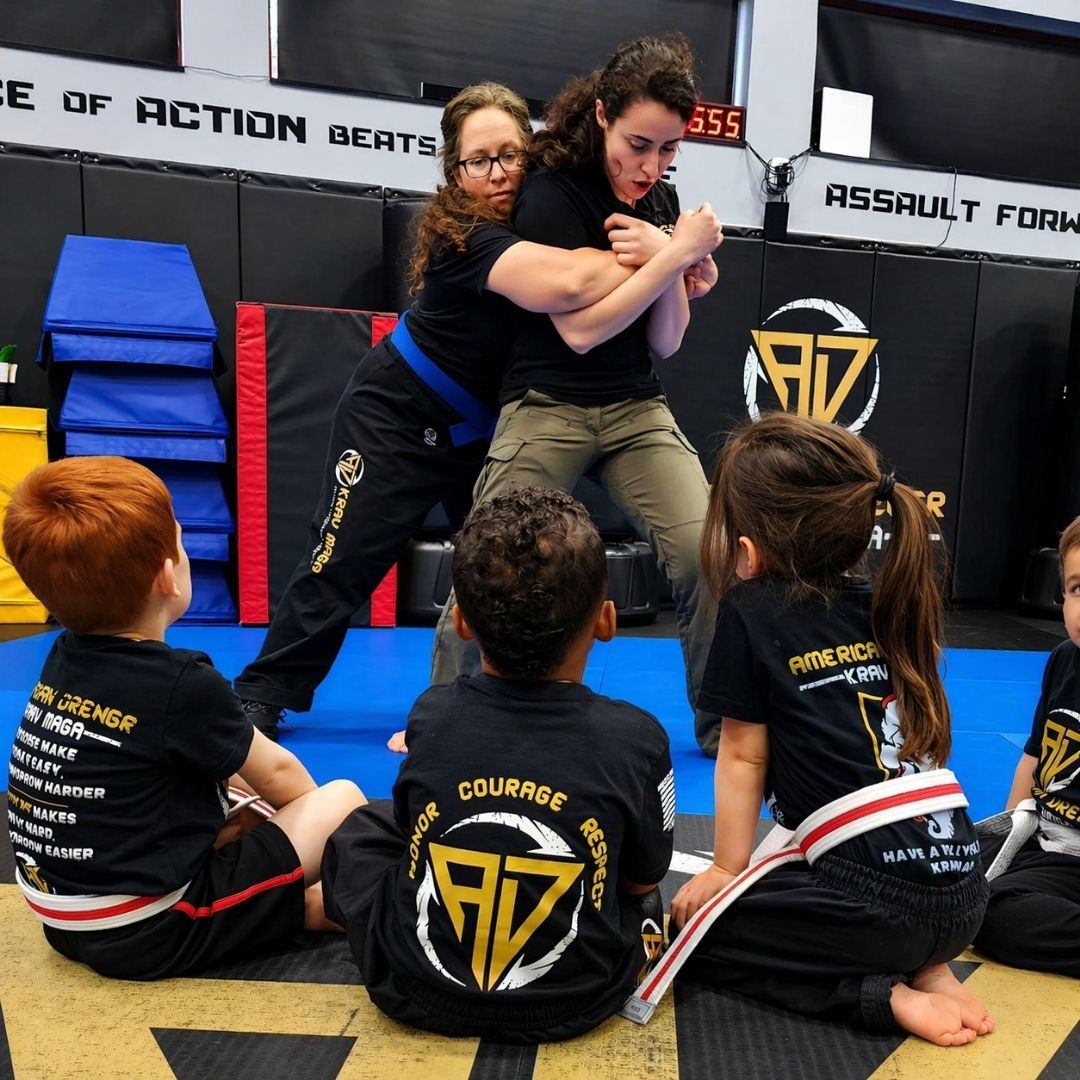 People practicing Brazilian Jiu-Jitsu. One person on the ground, another on top; two others grappling nearby. Black gis, indoor setting.