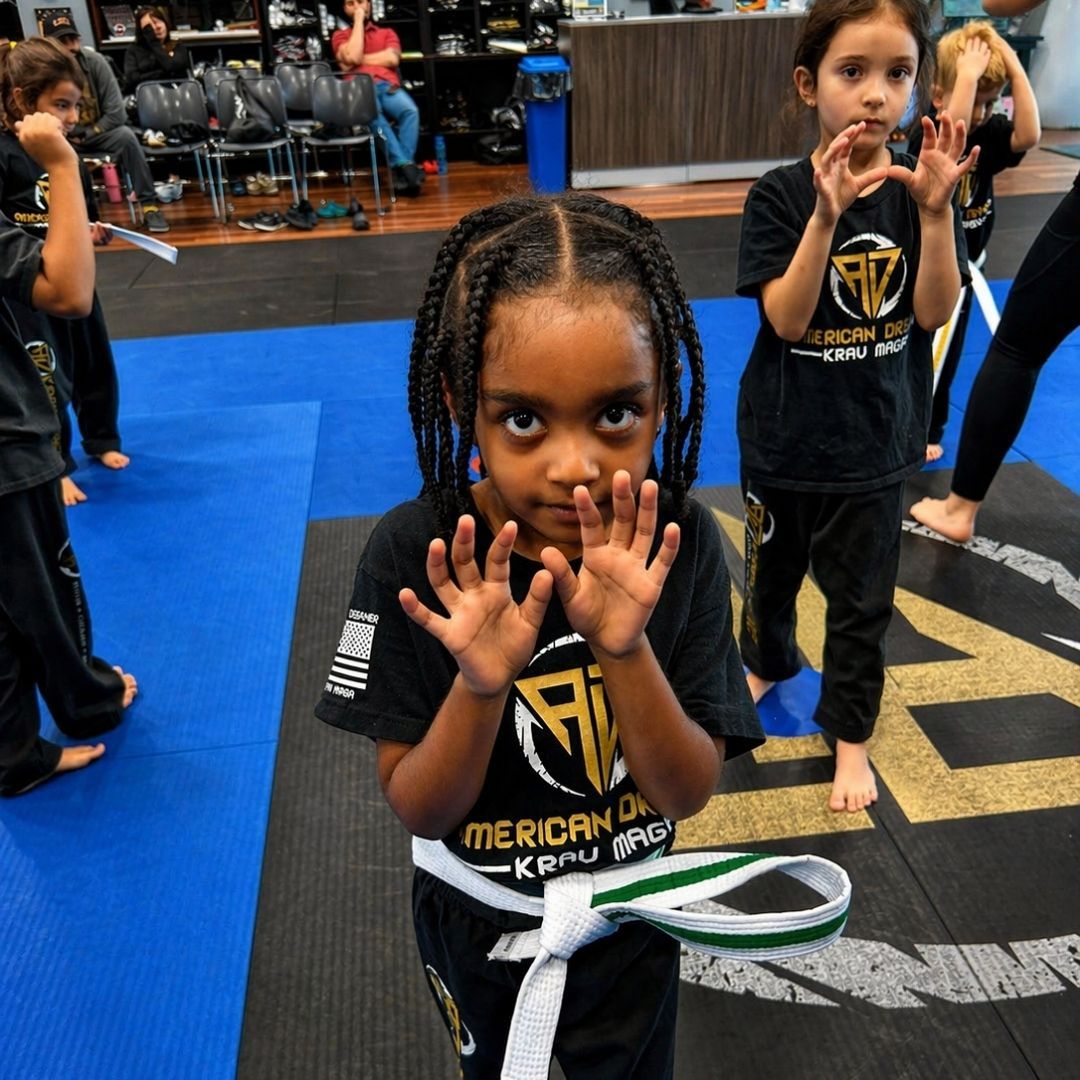 Two children grappling on a mat, one in a headlock.