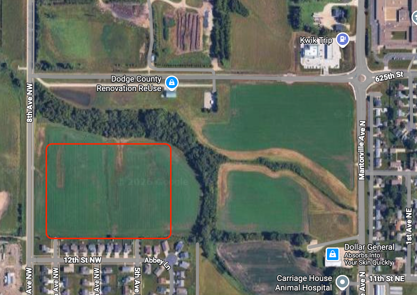 Satellite view of a marked rectangular field beside roads, trees, and nearby buildings.