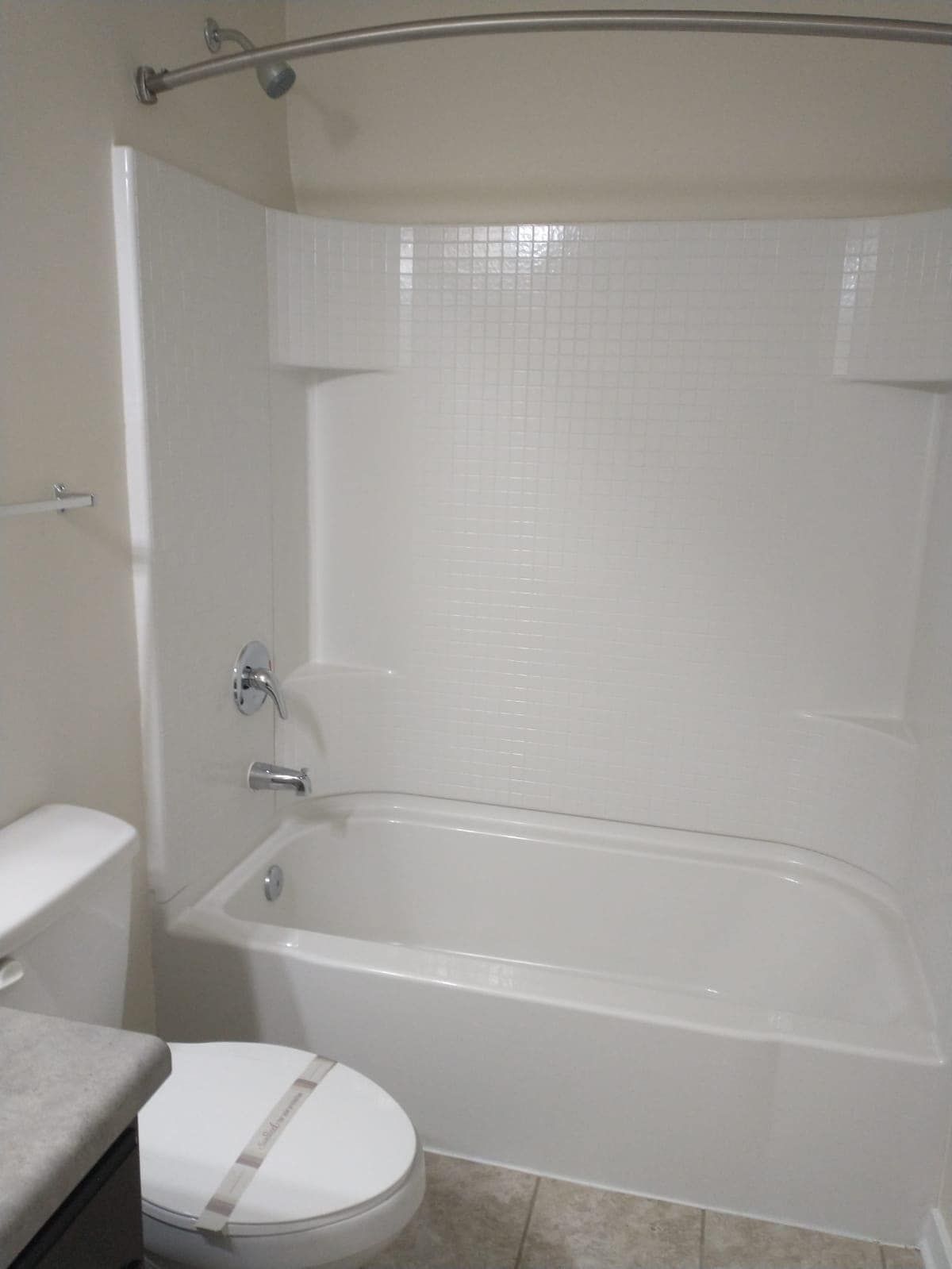 White bathroom with a tub, toilet, and shower surround.