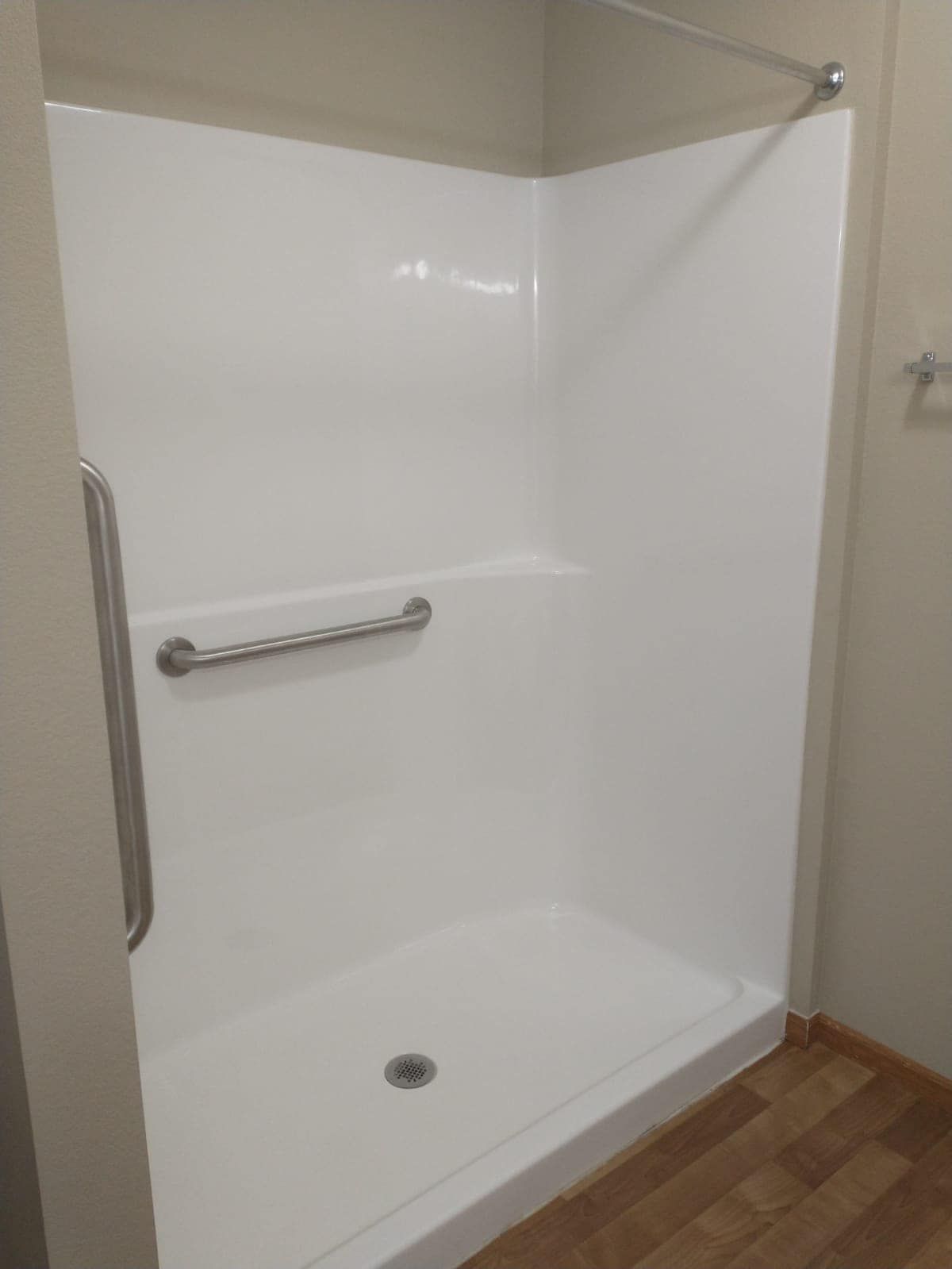 White accessible shower stall with grab bars and a low threshold.