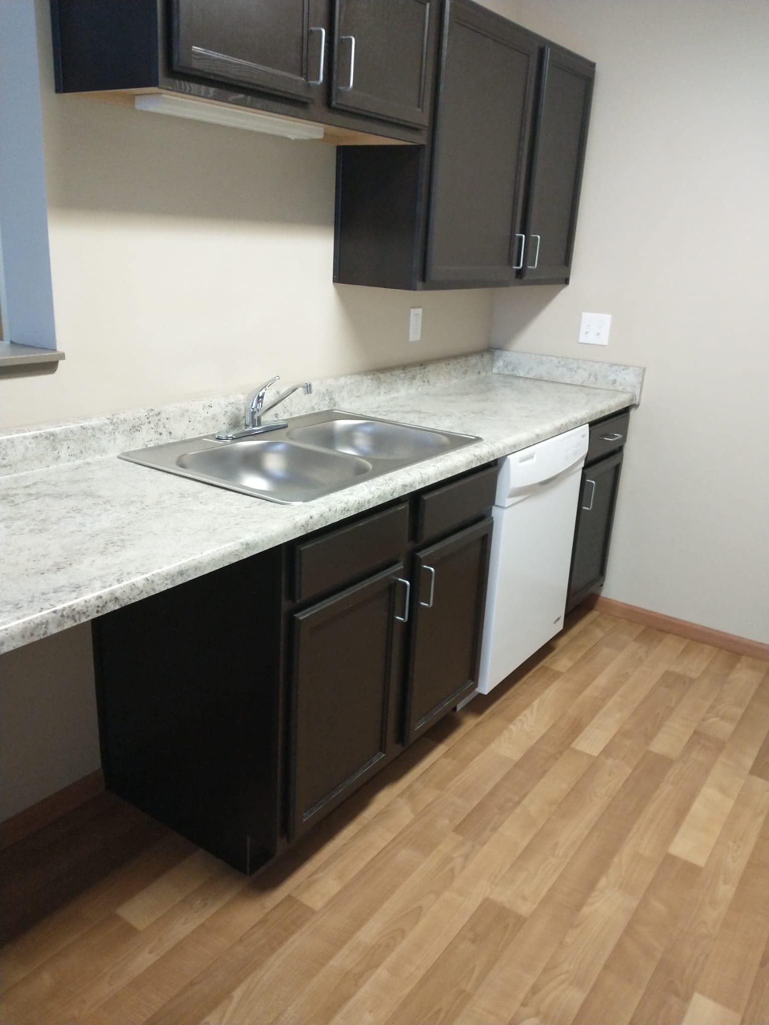Kitchen with dark brown cabinets, light countertops, stainless steel sink, and white appliances.