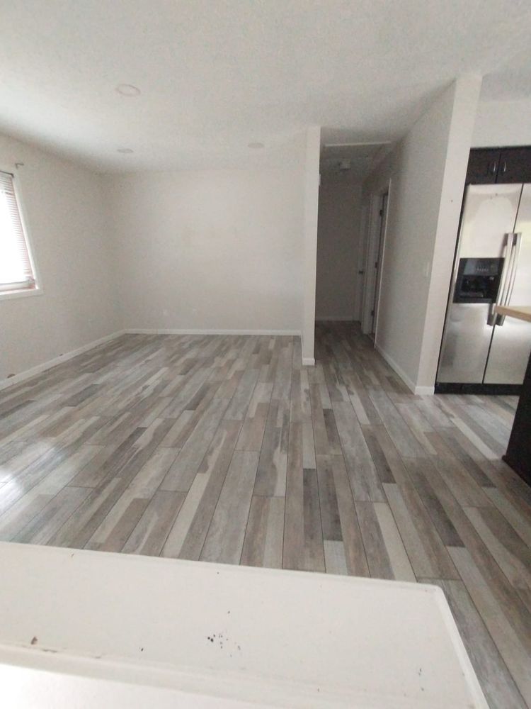 Empty room with gray wood-look flooring, white walls, and a doorway leading to a hallway.