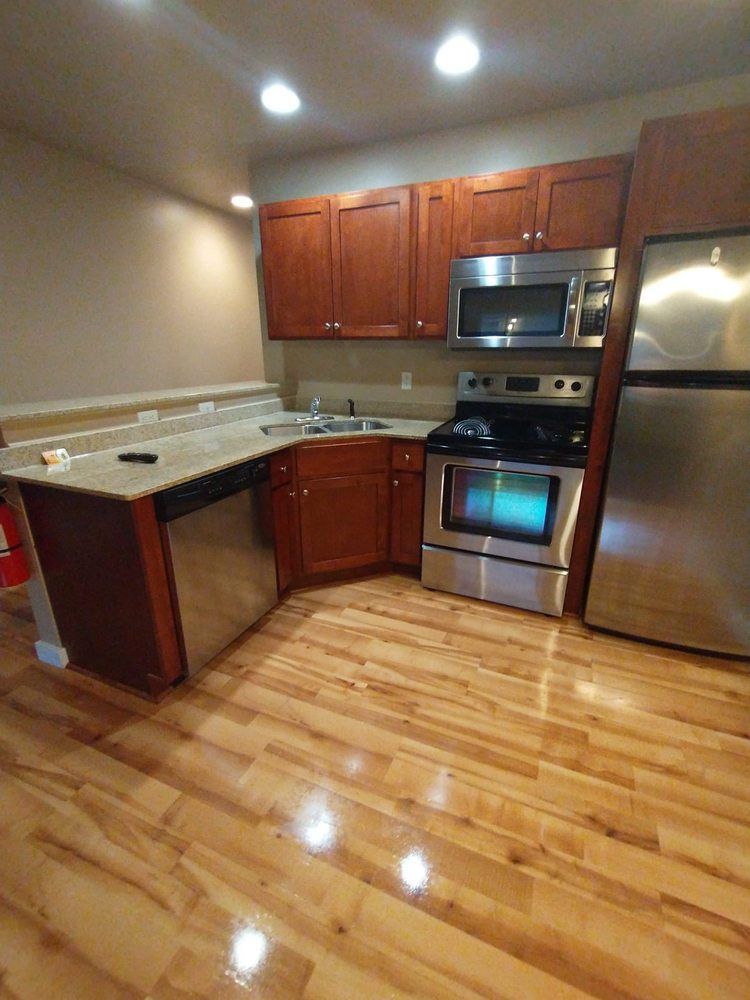 Kitchen with wood cabinets, stainless steel appliances, and wood flooring.