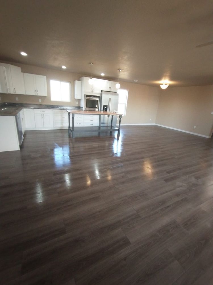 Spacious open-concept kitchen and living room with dark wood-look flooring and white cabinetry.