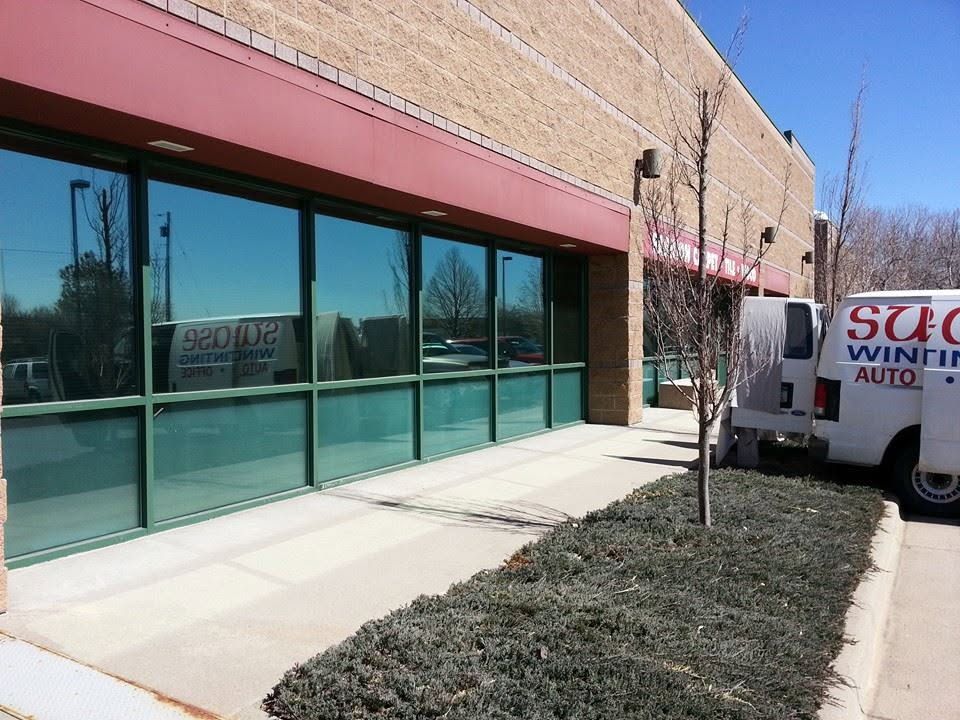 Storefront with large windows, red awning, and a white van parked beside a brick building.