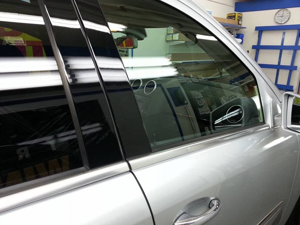 Silver car side window and door in a garage, with reflections visible on the tinted glass.