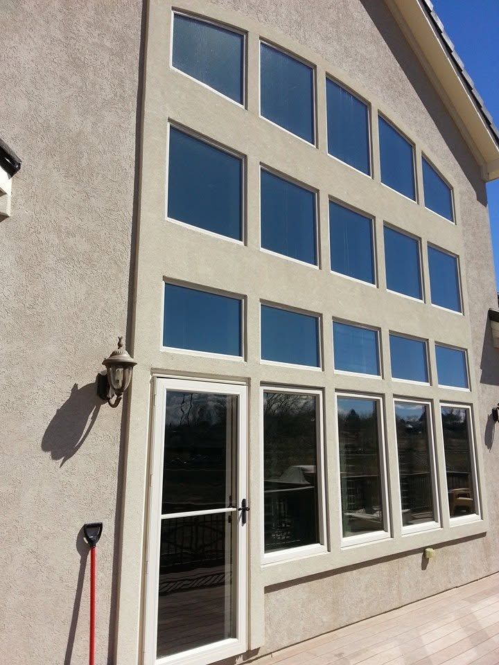 Exterior of a beige building with large blue-tinted windows and glass doors, viewed from the side.