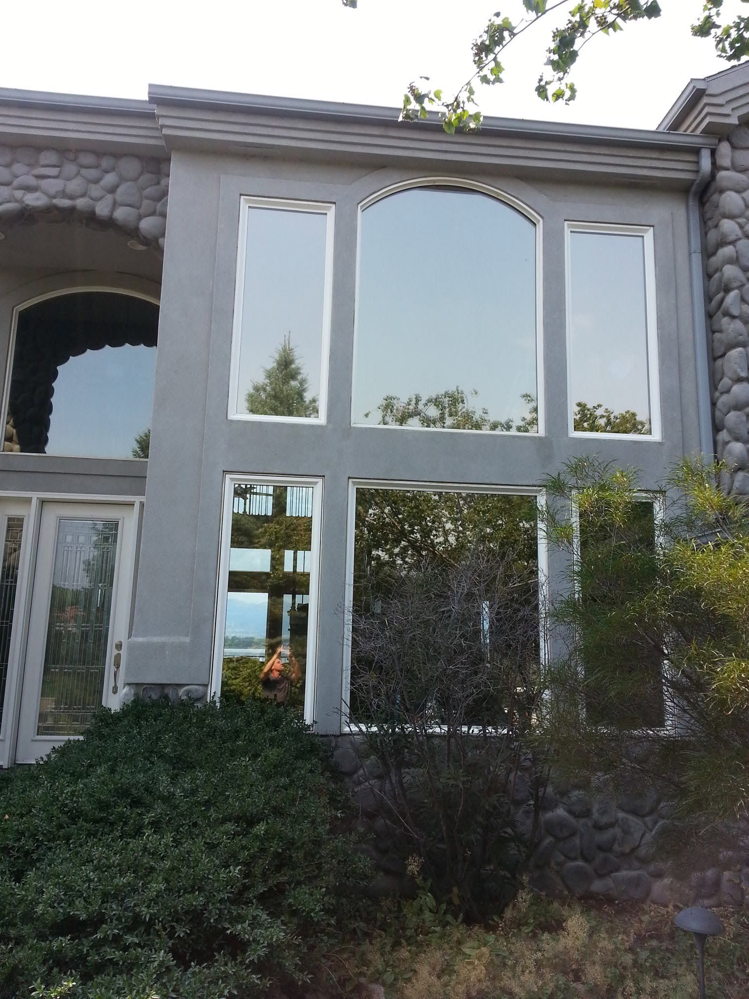 Stone building facade with large white-framed windows and shrubs in front