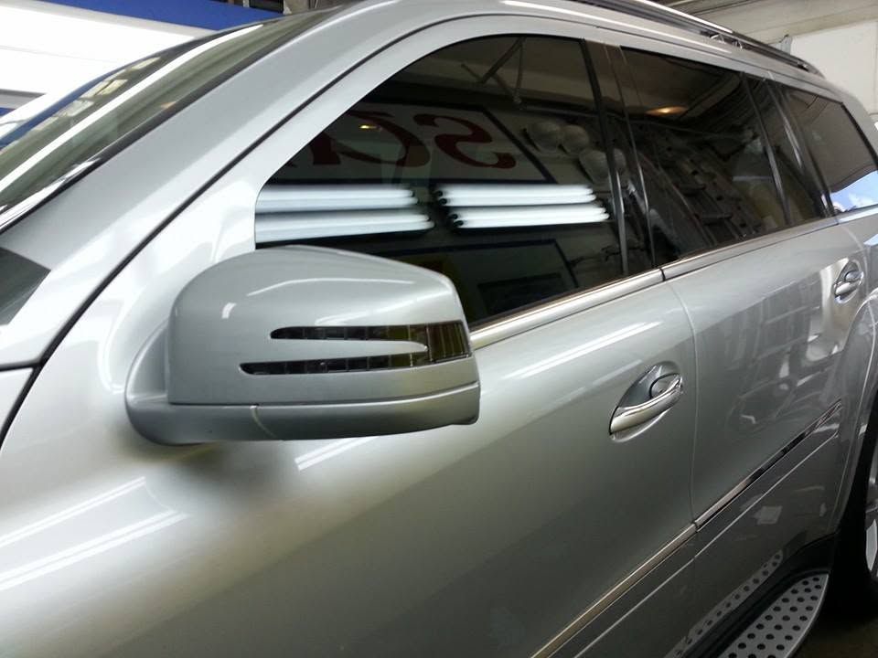 Silver SUV side view with tinted windows and side mirror in a garage