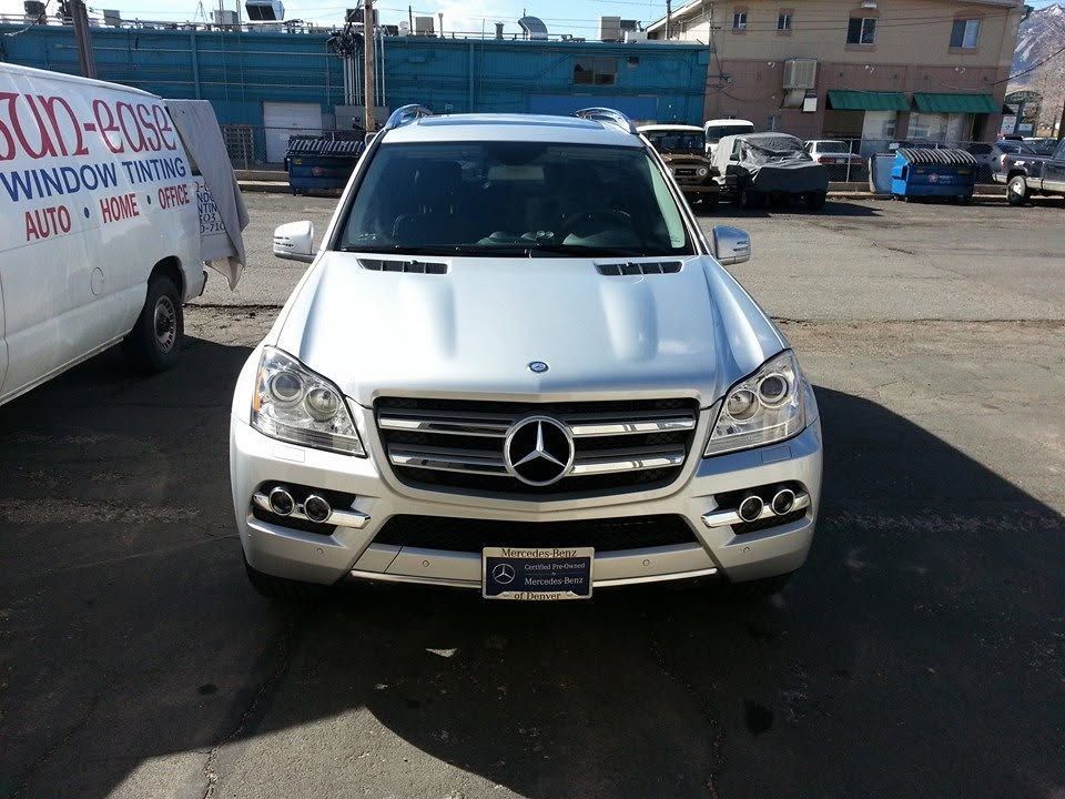Front view of a silver Mercedes SUV parked in an outdoor lot with buildings in the background
