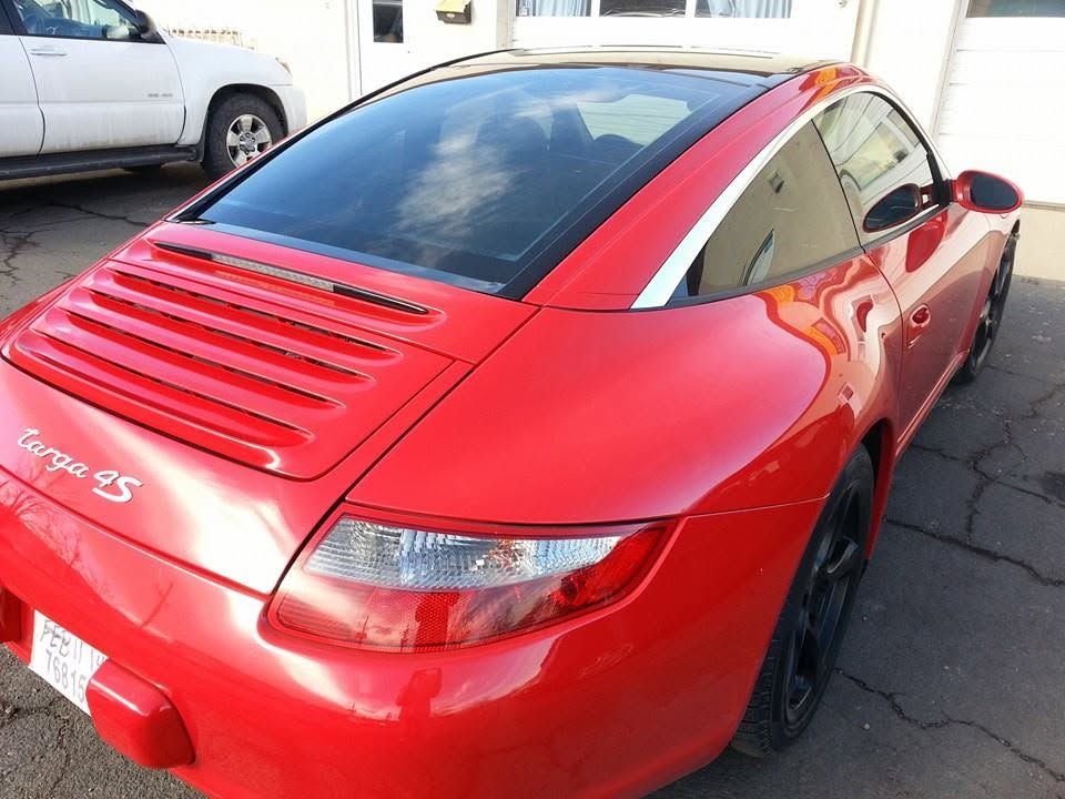 Red Porsche 911 Carrera S parked outdoors, rear three-quarter view, with red paint and black wheels